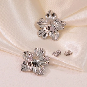 Détail de boucles d'oreilles fleur en acier titane argenté avec pétales texturés