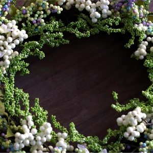 Artificial white berry wreath with green foliage on a dark wooden background