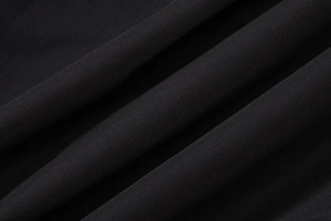 Macro shot of black fabric texture with detailed pleats and woven patterns for dresses