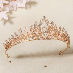 Detailed view of a golden bridal crown with crystal leaf patterns on a beige background