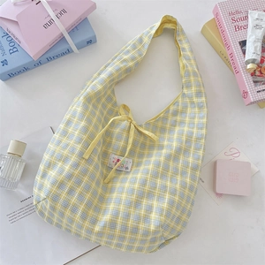 Detail of yellow plaid tote bag featuring a cute bow and woven label design