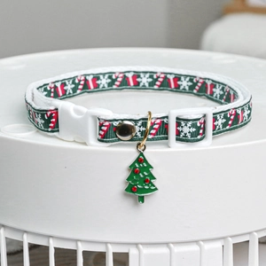 Detail of green Christmas dog collar with candy cane patterns and a tree charm
