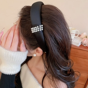 Detail of elegant black fabric headband with double row pearl accents on a female model