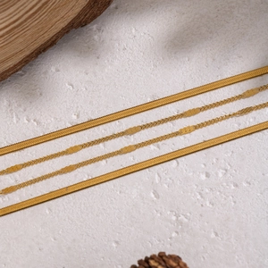 Double layered gold snake chain necklace with heart pendant on stone background