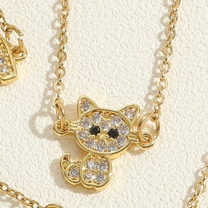 Macro view of gold cat pendant necklace with sparkling white zircons and black stone eyes
