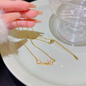 Detail of gold Queen pendant necklace with crown design and sparkling cubic zirconia crystals
