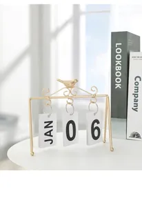 Detail of creative bird perpetual calendar with gold metal frame on a white table