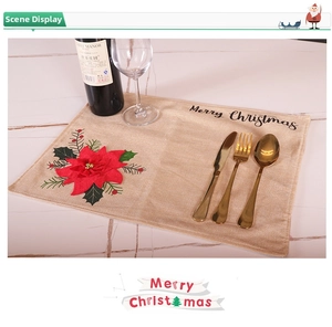 Linen Christmas placemat with red poinsettia and Merry Christmas print on marble table