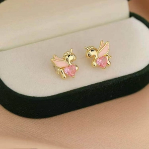 Golden unicorn stud earrings with pink heart crystals on a velvet jewelry display