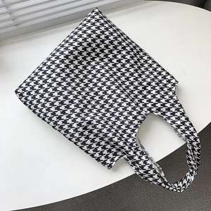 Detail view of retro houndstooth canvas tote bag texture on a minimalist white surface
