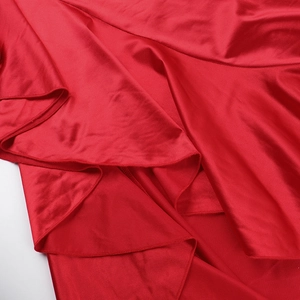 Vue macro détaillée de l'ourlet à volants et du tissu en satin rouge lisse de la robe de soirée