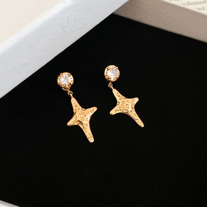 Macro detail of gold-plated star earrings with sparkling cubic zirconia on a velvet background