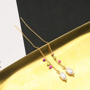 Detail of gold tassel threader earrings featuring colorful beads and drop pearls
