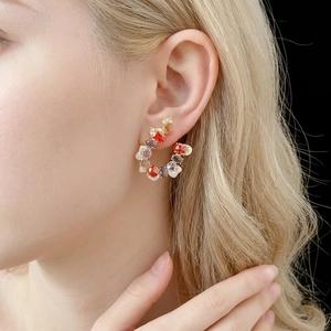Vintage-style gold C-shaped earrings with colorful gemstones on a female model