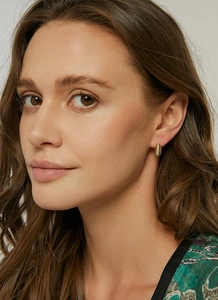 Close-up of golden croissant hoop earrings with textured finish on a female model