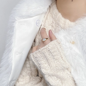 Close-up of a vintage gold opal ring worn with a cozy white knit sweater background