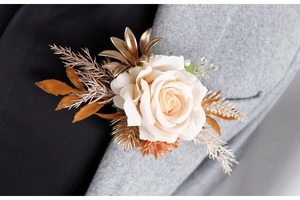 Détail d'une boutonnière en rose de soie crème sur un costume gris avec accents dorés