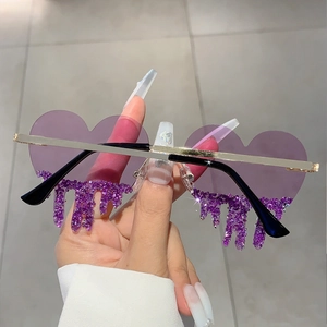 Close-up of heart-shaped rimless sunglasses with purple gradient lenses and dripping rhinestones