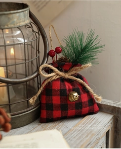 Close-up of buffalo plaid Christmas gift bag with pine cones and berries on wood