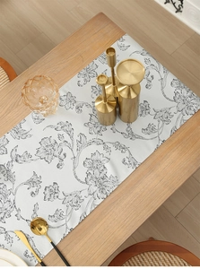 Detail of black and white floral jacquard table runner with elegant gold tableware