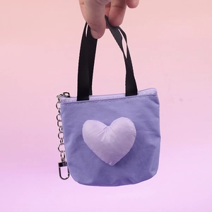 Detalle de un mini llavero de bolso morado con forma de corazón y clip metálico