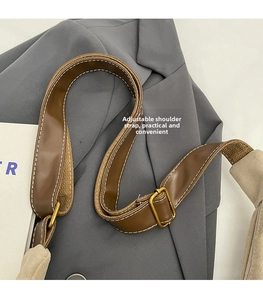 Close-up of adjustable brown leather shoulder strap with bronze metal buckle detail