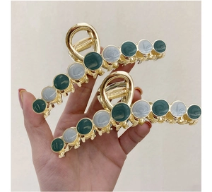 Detail of large metal hair claw clips with marble resin stones and golden alloy finish