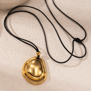Macro shot of gold organic fluid pendant on black cord with polished metallic texture