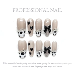 Detail view of handmade long press-on nails with 3D black bows and cow print design