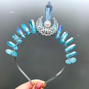 Macro detail of iridescent blue crystal shards and moon charm on a handmade crown headband
