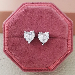 Close-up of heart-shaped silver earrings with sparkling stones in a pink velvet box