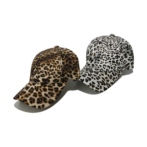 Detailed view of leopard print texture on two cotton twill baseball caps in brown and white