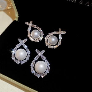 Macro shot of silver pearl earrings with rectangular zircon accents in a black velvet box