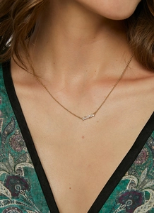Close-up of a gold necklace with horizontal zircon pendant on woman neck