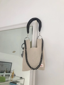 Detail of off-white crochet bag with hollow mesh texture and chunky black chain