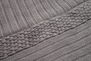 Close-up of dark grey knitted fabric showing soft ribbed and seed stitch textures