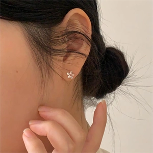 Minimalist S925 sterling silver flower stud earrings worn on a female model earlobe