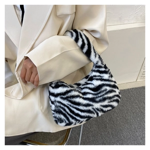 Detail shot of zebra print faux fur shoulder bag styled with a chic beige blazer