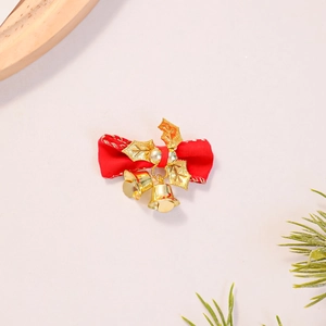Close-up of red Christmas bow hair clip with golden holly leaves and small bells