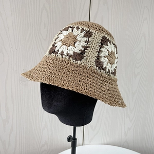 Detail of hand-woven straw hat featuring intricate crochet floral patterns and textures
