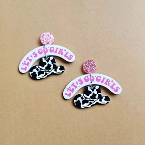 Detail of Let's Go Girls pink glitter earrings with acrylic cow print cowboy hat charms