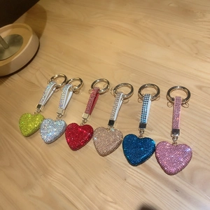 Sparkling crystal heart keychain pendants in multiple colors on a light wooden desk