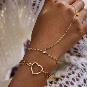 Détail d'un bracelet cœur doré et d'une chaîne de main avec cristaux étincelants