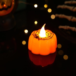 Detail of orange LED pumpkin candle with black spider web pattern for Halloween decor