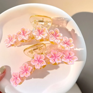 Pink resin cherry blossom hair claw clips in a white ceramic dish, sweet floral accessories