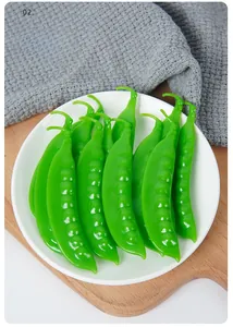 Close-up of realistic green PVC pea pods on a white ceramic plate for food photography