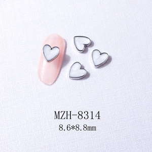 Macro view of heart nail charms with white shell texture and silver metal border
