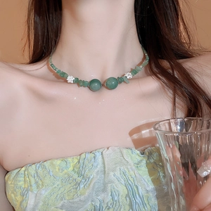 Dettaglio di una collana di giada verde con ciondoli a loto in argento sul collo di una modella
