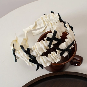 Detail of white ruffled pleat headbands with small black bows on a ceramic cup