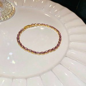 Close-up of elegant gold-plated tennis bracelet featuring oval-cut purple zircon gemstones